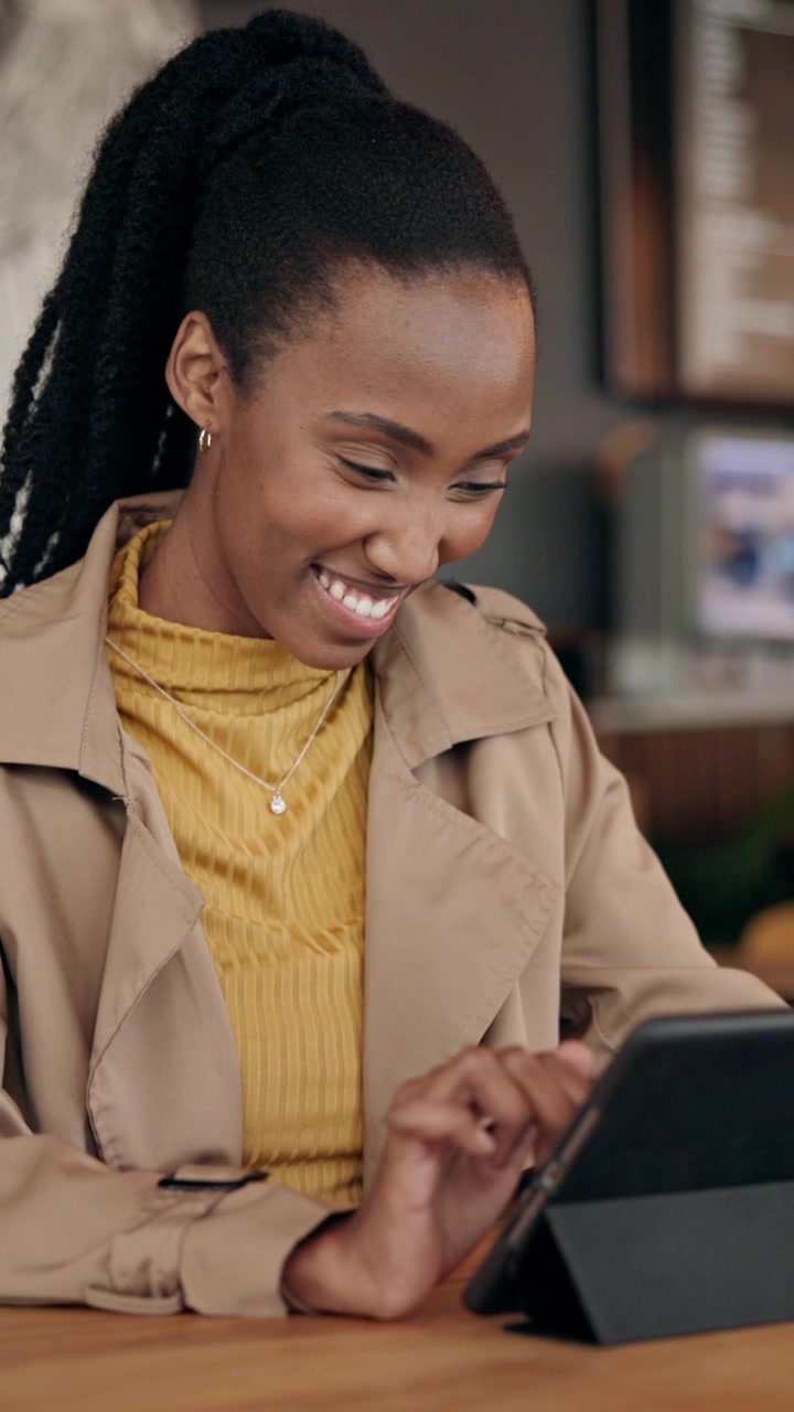 Smilende ung kvinde bruger tablet på moderne café