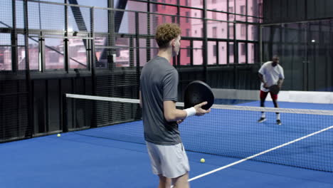 two diverse men playing padel tennis on indoor court, focused and ready for action