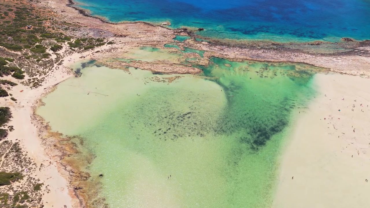 Flygfoto med drönare över sandbankar och klipprev i det grunda turkosa vattnet i Baloslagunen, Balos, Grekland