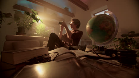 man with vintage camera and globe in a hazy study