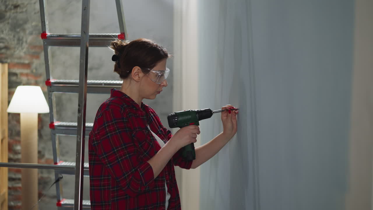 Una donna con occhiali di plastica sceglie un punto dove avvitare nel muro