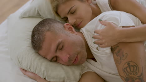 Peaceful-woman-lying-in-bed-with-husband-and-kissing-him