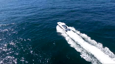 Top-down-view-of-boat-riding-in-the-open-ocean-with-blue-water-and-sunny-skies