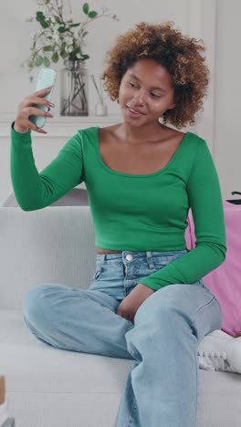 woman in green top relaxes on couch at home during cozy afternoon