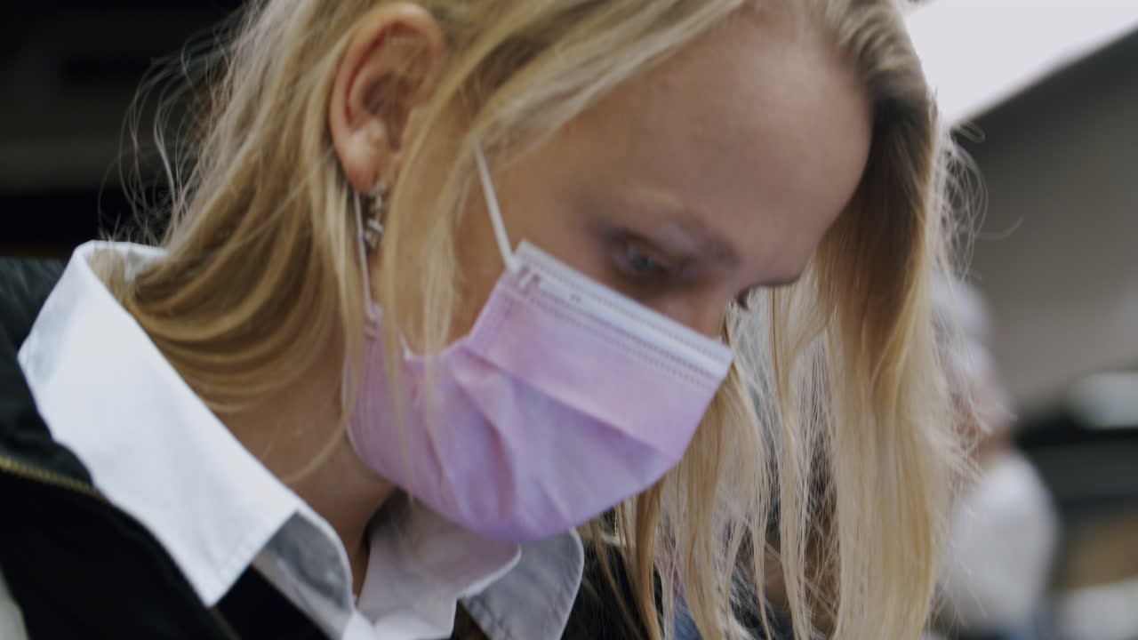 женщина в маске, отправляющая смс в метро.