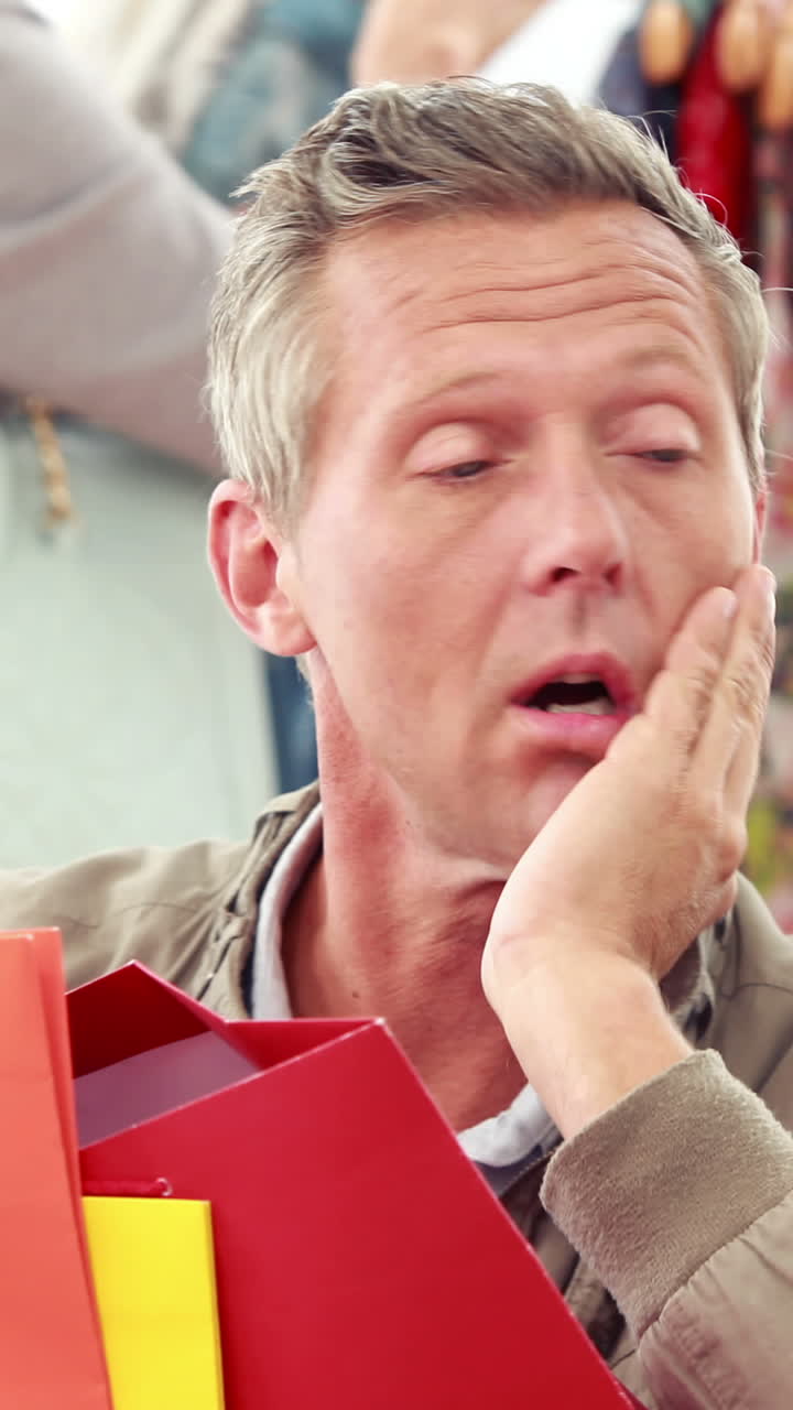 여자친구 앞에 앉아 쇼핑 가방을 가진 지루한 남자