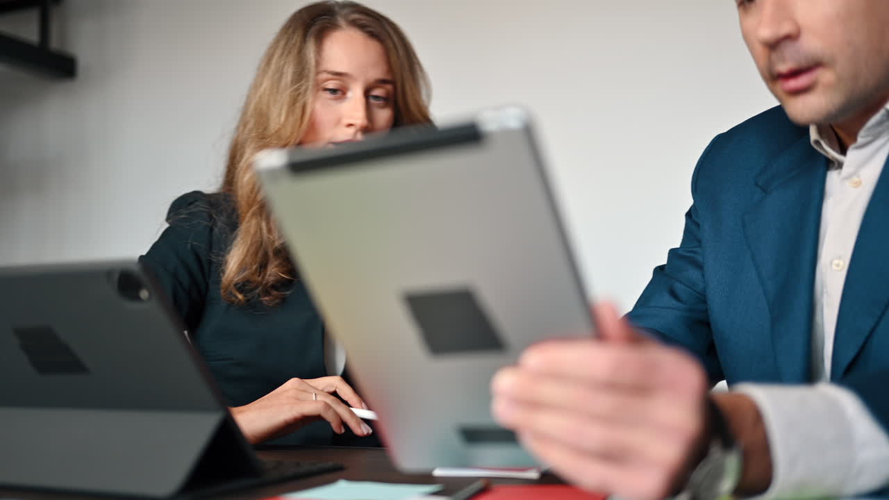 Coworkers talking while pointing at a tablet in an office