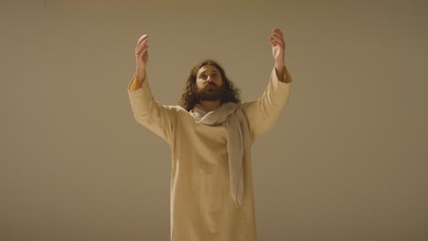 portrait of man wearing robes with long hair and beard representing figure of jesus christ raising hands in prayer 2