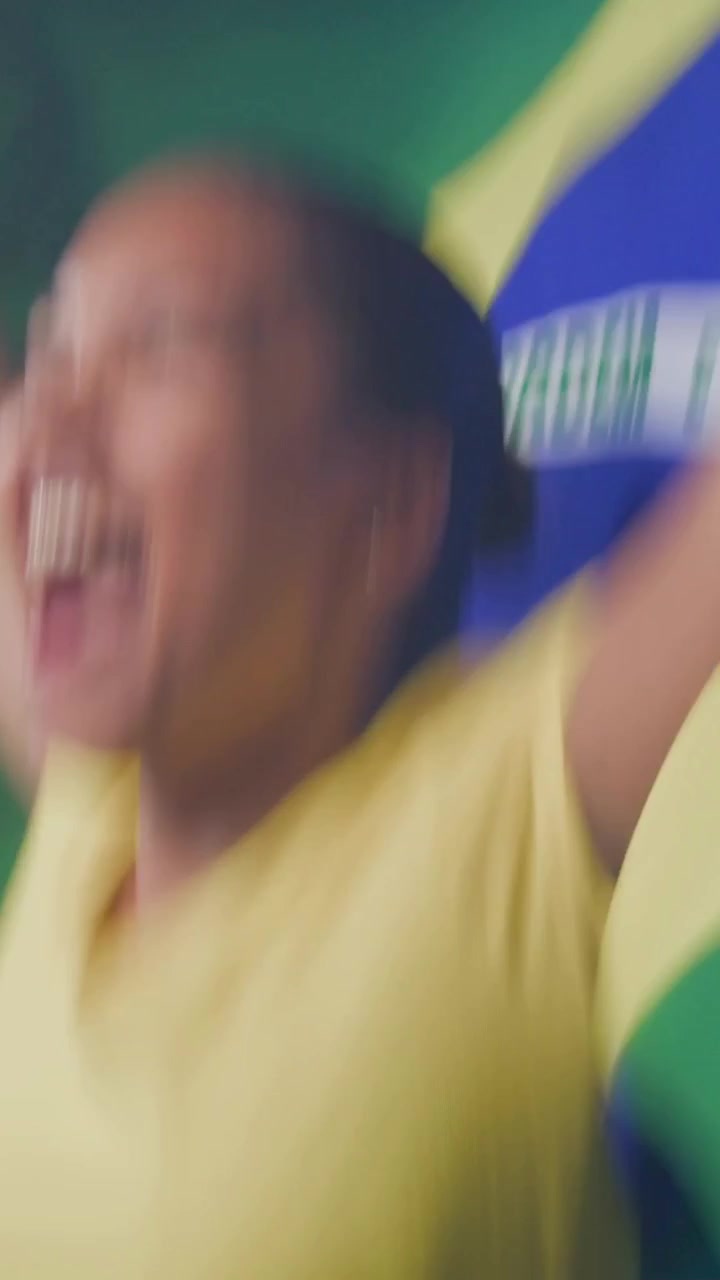 Video verticale: Donna che urla con top giallo che sventola la bandiera del Brasile durante un allontanamento della telecamera, con spazio per il testo