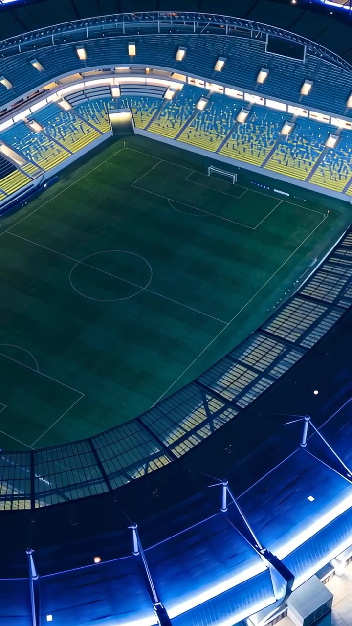 Video verticale: Telecamera aerea rotante che rivela un campo vuoto e una porta di notte, mostrando LED blu.