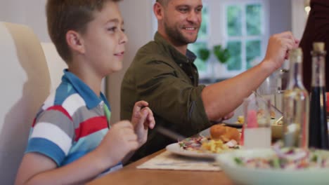 Smiling-caucasian-family-at-table-serving-each-other-food-before-meal