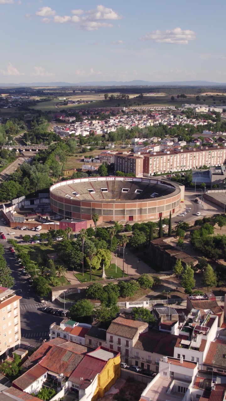 Scenic vertical aerial shot flying over Badajoz toward the iconic Plaza de Toros, emphasizing architecture and cultural heritage.