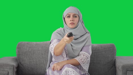 angry muslim woman trying to fix television remote green screen