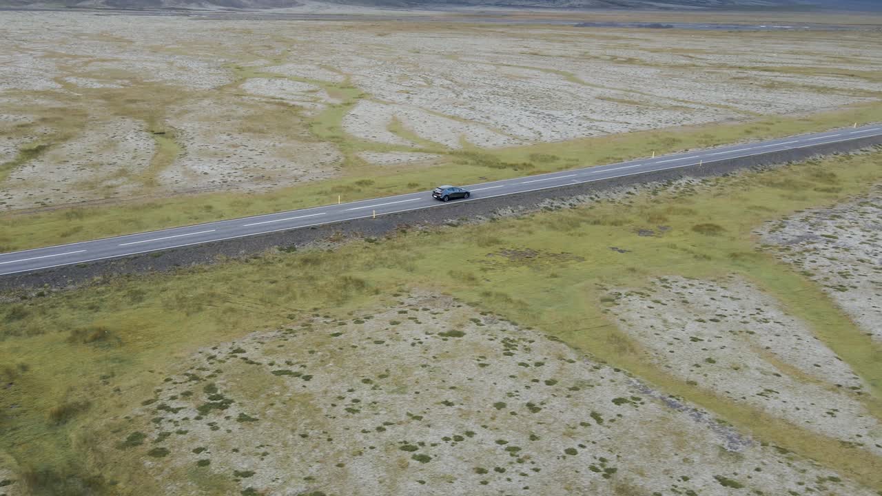 Traverse Iceland's scenic expanses with this captivating 4K drone footage, featuring a unique arial view as a car drives through the bare countryside of Iceland