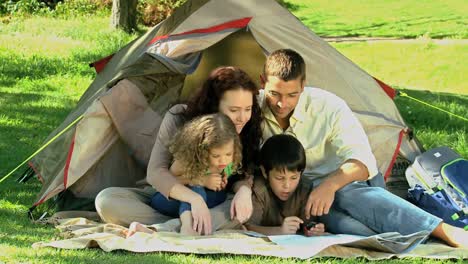 Family-looking-at-a-map-siiting-in-front-of-a-tent
