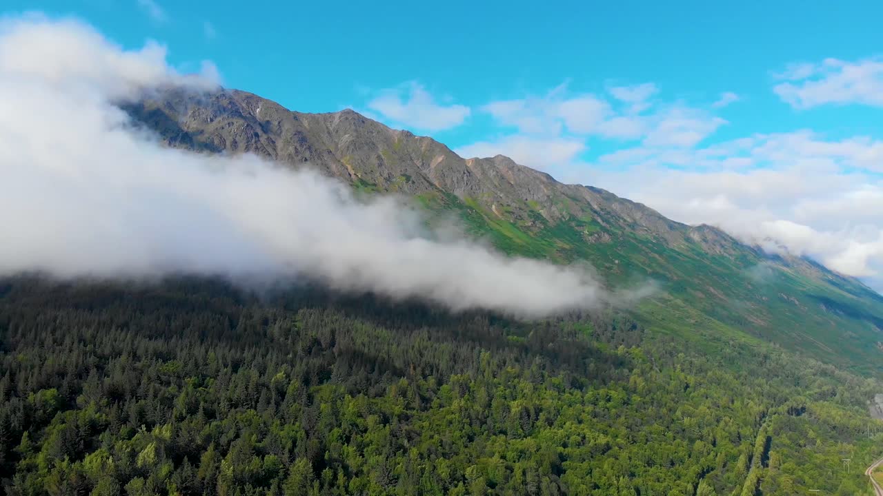 video de dron de 4k de nubes de baja elevación corriendo a través de una empinada montaña cubierta de hierba en la costa del brazo turnagain, alaska en verano