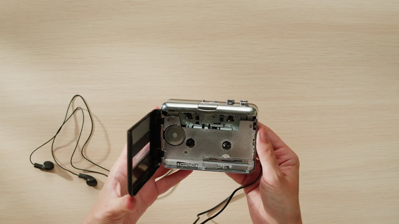 manos sosteniendo un reproductor de cassette portátil de época con auriculares