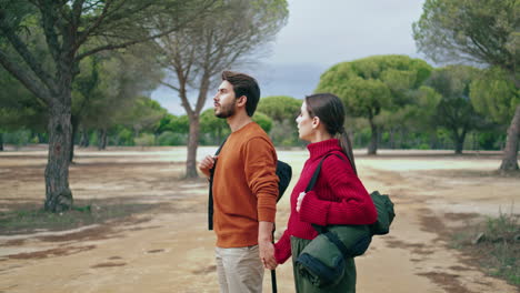 Active-pair-walking-nature-with-backpack-looking-on-autumn-landscape-vertical