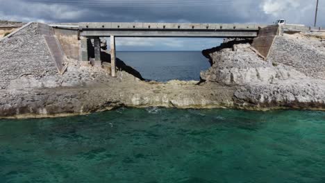 cinematic aerial view drone shot flying under glass window bridge on the island of eleuthera in the bahamas - separating the atlantic ocean from the caribbean sea