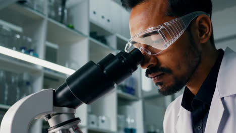 a male scientist conducting research and taking notes in a laboratory with a microscope