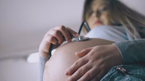 La-Mujer-Embarazada-Con-El-Vientre-Escucha-Los-Latidos-Del-Corazón-Del-Bebé.