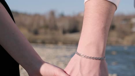 close-up of hands joining together near river in the mountains. beautiful romantic moment between two lovers