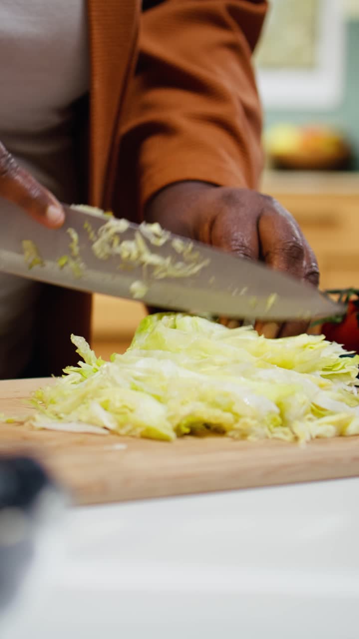 Video verticale. Food blogger di colore taglia lattuga iceberg sul tagliere
