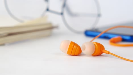 orange earbuds on a white desk