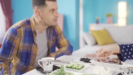 restless and unhappy married couple fighting each other at breakfast table in the morning.