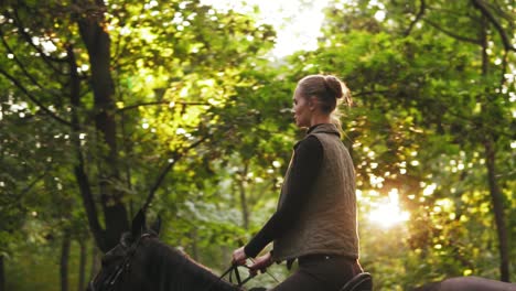 reiten im sommerwald. junge weibliche reiterin auf dem pferd in einem schattigen waldgalopp.