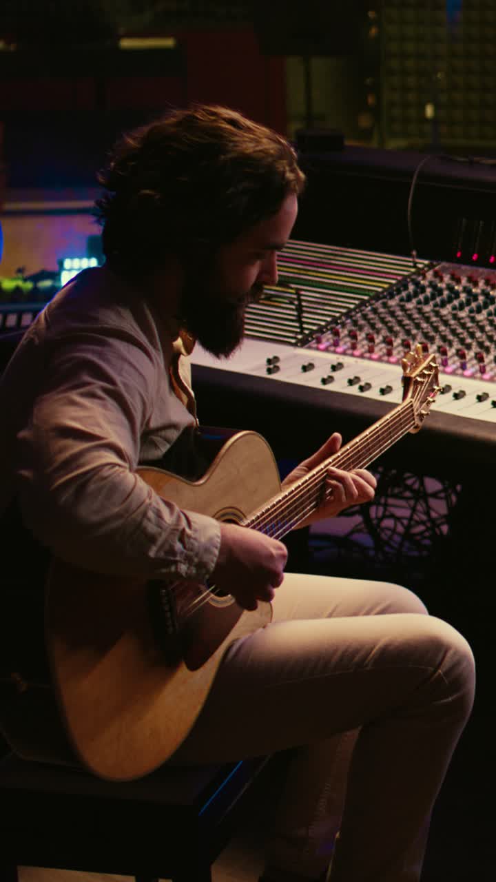 Uomo che suona la chitarra acustica in uno studio musicale buio