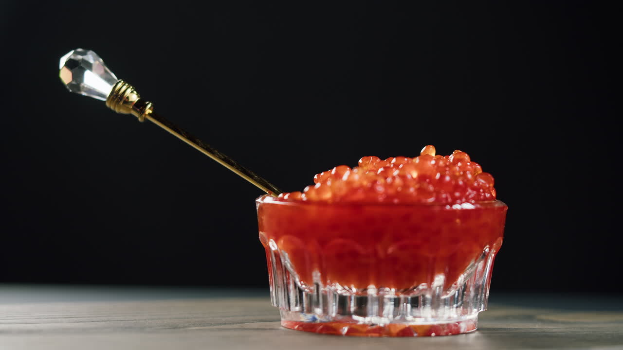 Servire caviale rosso con un cucchiaio in una piccola ciotola di vetro