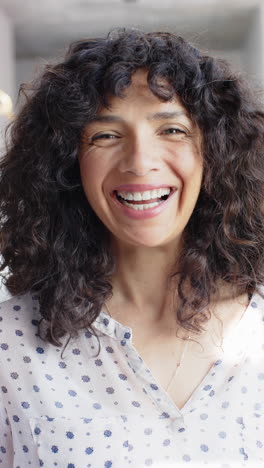 vertical video of portrait of happy biracial woman with curly hair at home, slow motion