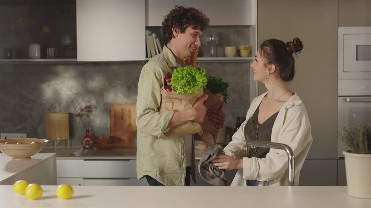 Couple unpacking groceries in modern kitchen