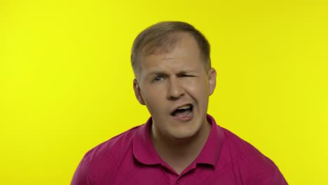 portrait of young caucasian man posing in pink t-shirt. dissatisfied, picky guy looking to camera