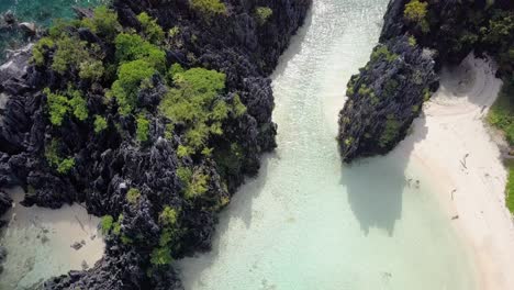 aerial of hidden beach pedestal down tilting up on limestone cliffs in el nido, palawan, the philippines