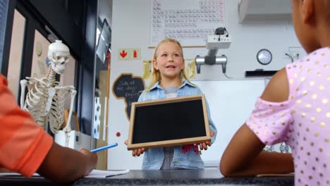 Vista-Frontal-De-Una-Colegiala-Caucásica-Enseñando-A-Escolares-En-El-Aula-4k