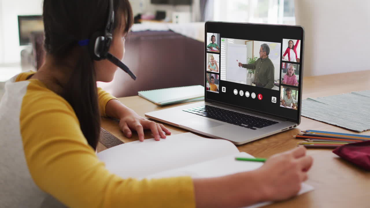Schoolgirl using laptop for online lesson at home, with diverse teacher and class on screen