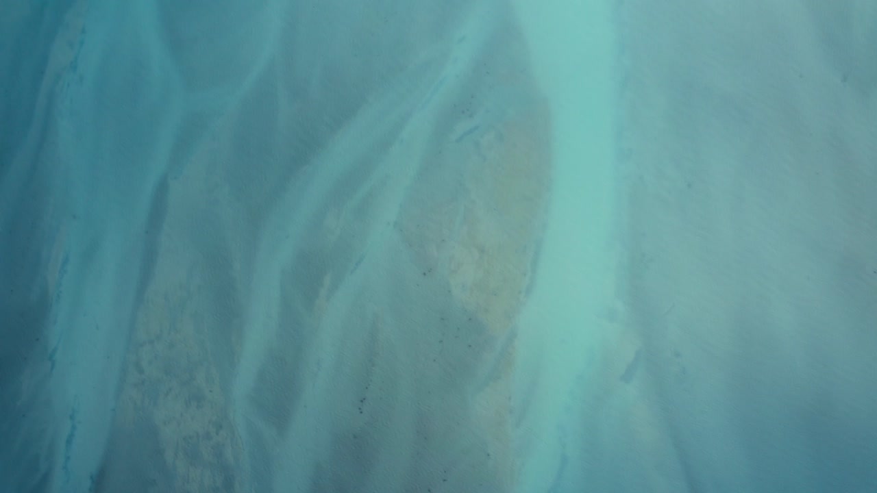 Top down drone shot of Beautiful Blue Water of Lake Tekapo transitioning into Braided River, New Zealand, South Island