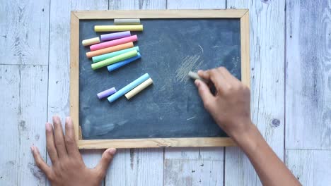 hand erases chalkboard with colorful chalks