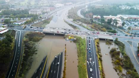 Schlammige,-überschwemmte-Wasserbecken-Und-Die-Zufahrt-Zur-Autobahn-Werden-Unterbrochen,-Wodurch-Sich-Der-Verkehr-Staut,-Panorama-Luftumlaufbahn