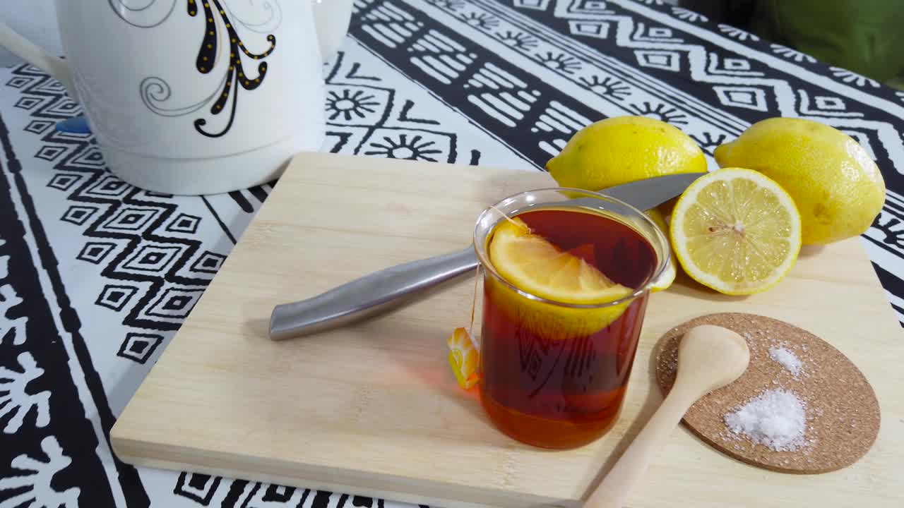 Preparing green tea with lemon wedges. On wooden cutting board.