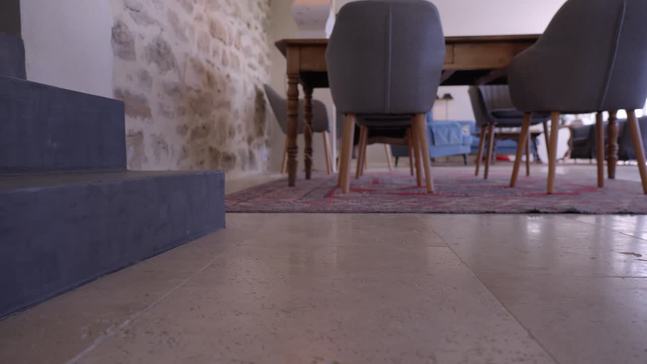 un ejecutivo ricamente vestido entra en una casa vieja, sus zapatos brillantes añadiendo un toque de lujo al entorno rústico