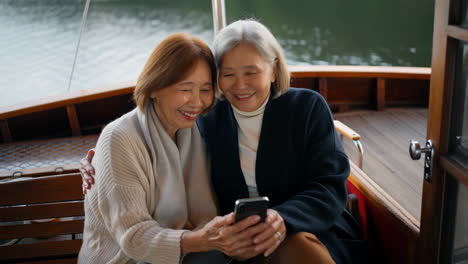 senior women enjoying boat ride with smartphone