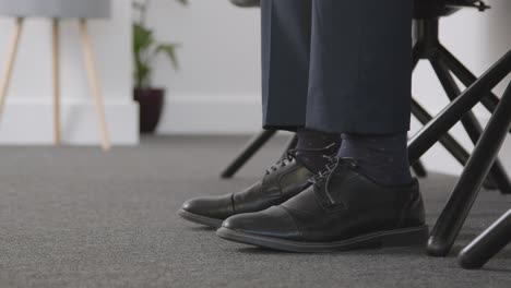 cerca de los pies del candidato masculino esperando en el cargo antes de la entrevista de trabajo