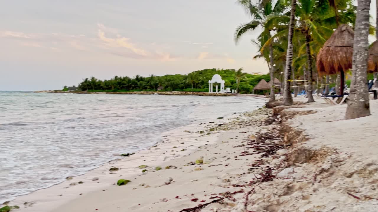 deslizamiento a la izquierda de una hermosa playa en tulum cerca de cancún, méxico con pequeñas olas, palmeras, cielo azul y algunas nubes