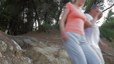 hombre ayudando a la mujer a hacer el camino en el bosque