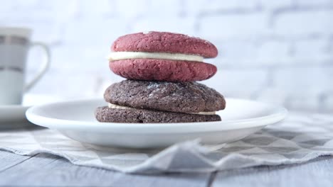 stack of pink and chocolate cream filled cookies on a plate