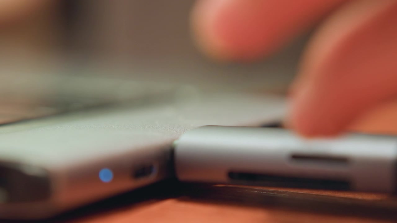 Close view of USB being connected. Office employee inserts flash drive into computer port with light. Person carefully plugs flash drive into computer port while indicator light glows