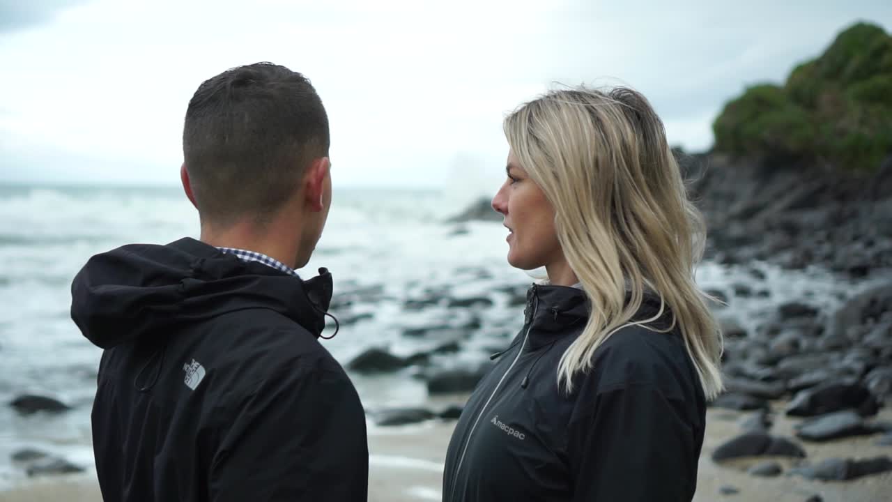 Young attractive couple from behind looking at ocean in New Zealand